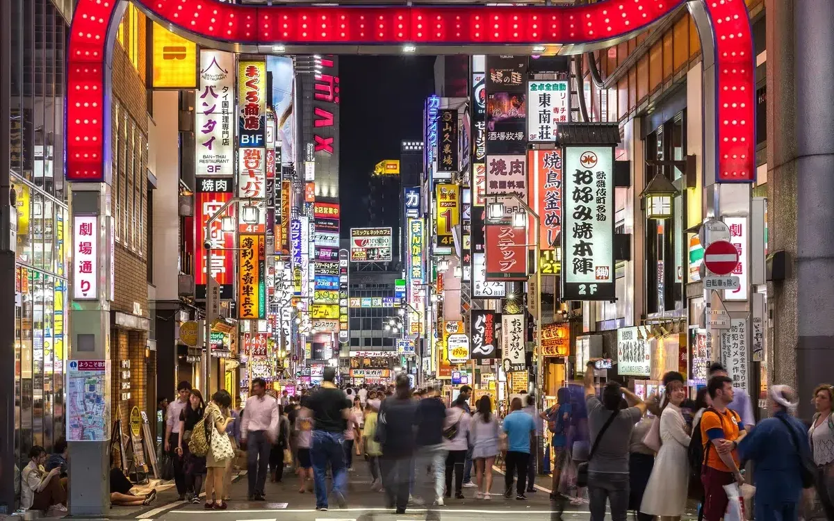 Calle comercial de Tokio iluminada con letreros de neón por la noche